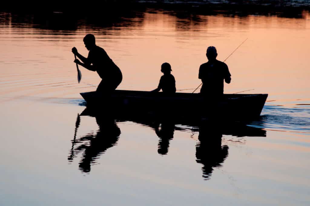 Kids fishing with parent at dusk stock image