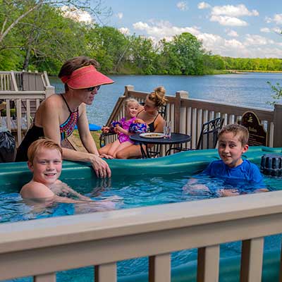 Children in hot tub with Mom and family in background with view of lake.
