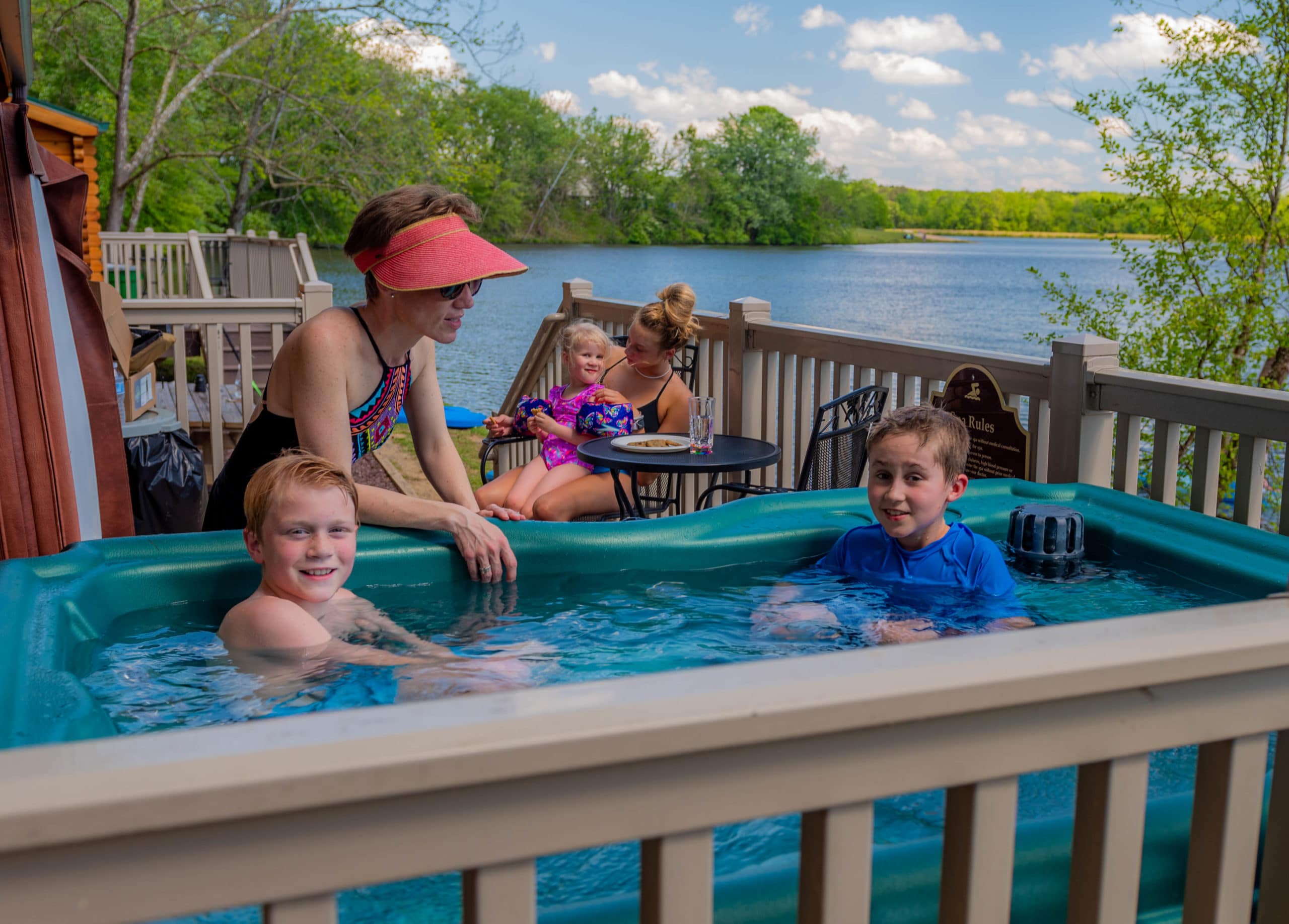 Boys in hot tub on camp cottage deck with Mom and family in background