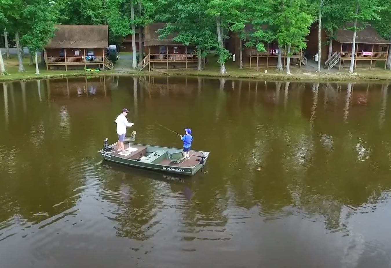 Fishing Boat on lake with log cabins