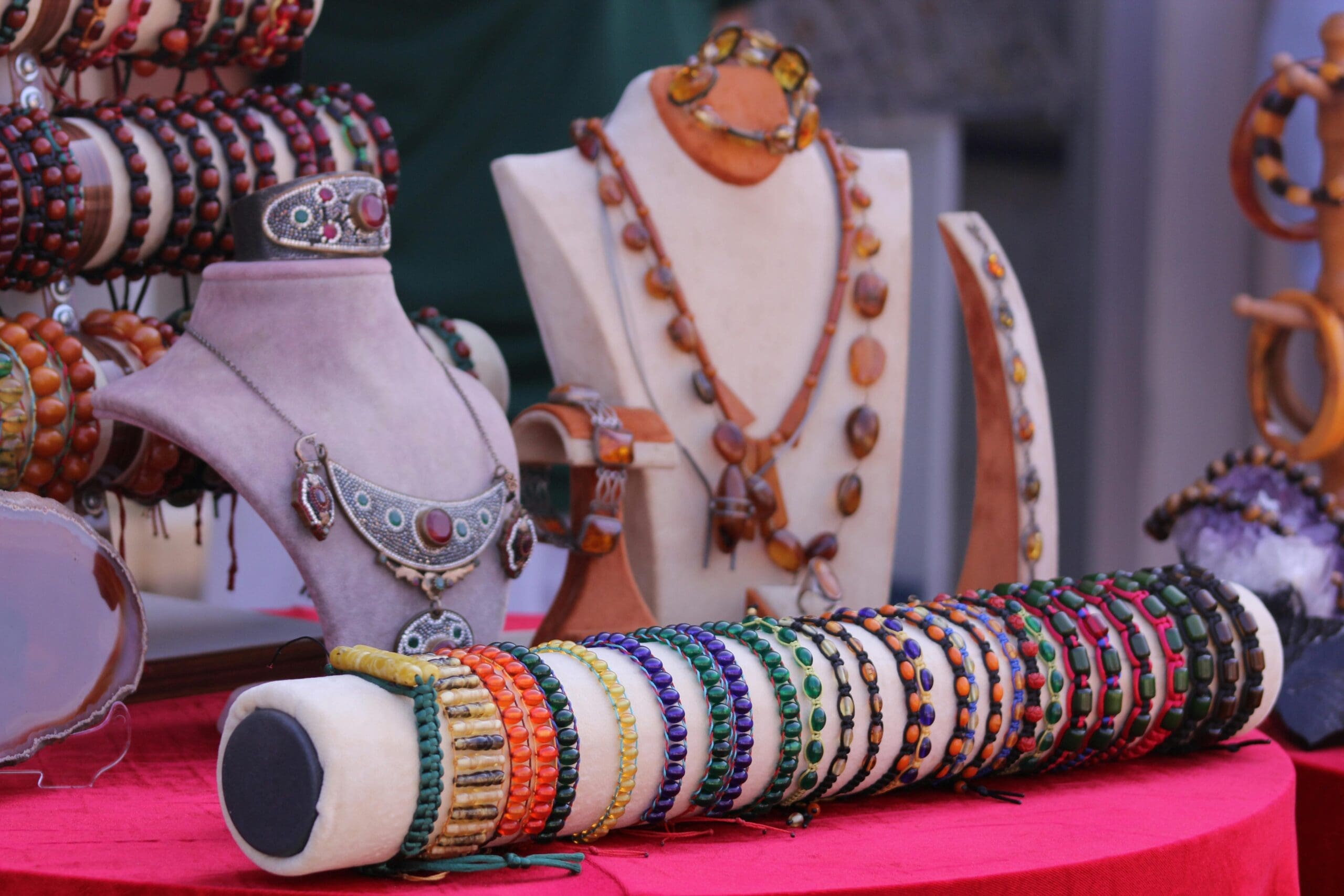 Showcase of colorful handcrafted bracelets and necklaces on soft velvet stands.