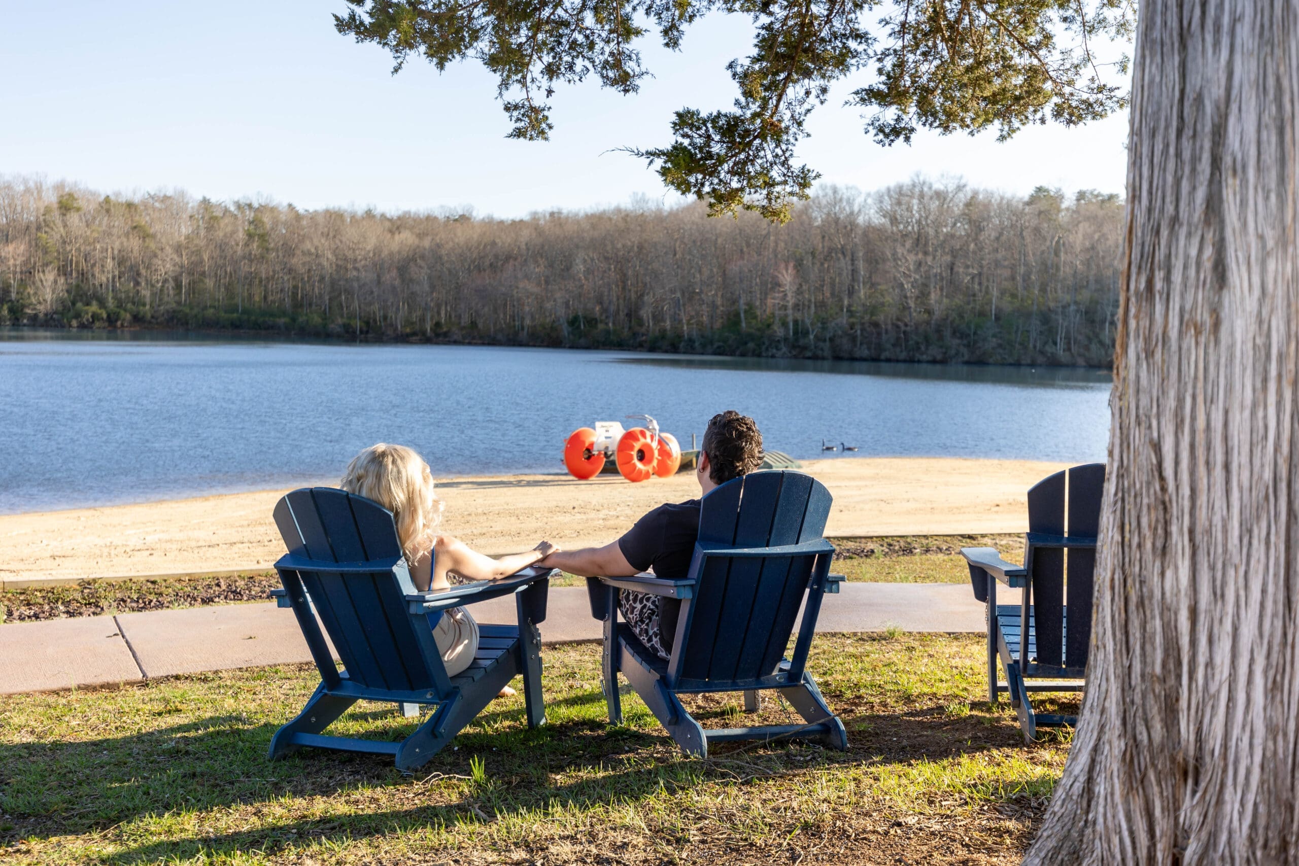 Couple relaxing in Adirondack chairs overlooking the private lake